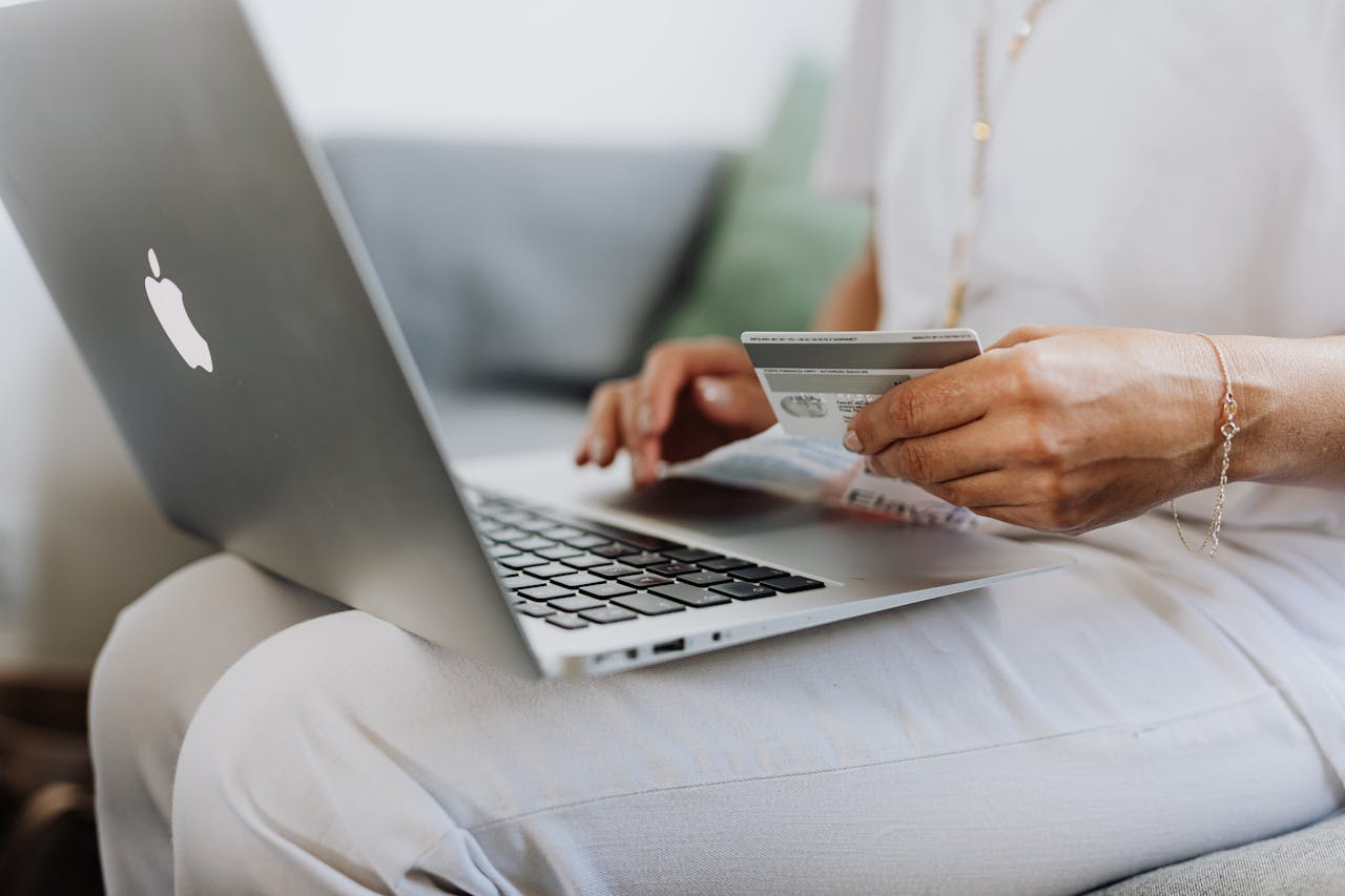 Crafting Captivating Headlines: Your awesome post title goes here Close-up of a person holding a credit card while shopping online using a laptop at home.