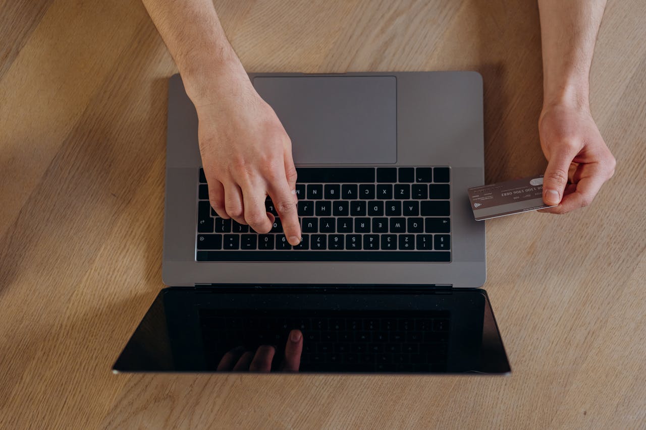 The Art of Drawing Readers In: Your attractive post title goes here Top view of hands using a credit card and laptop for online transactions on a wooden surface.